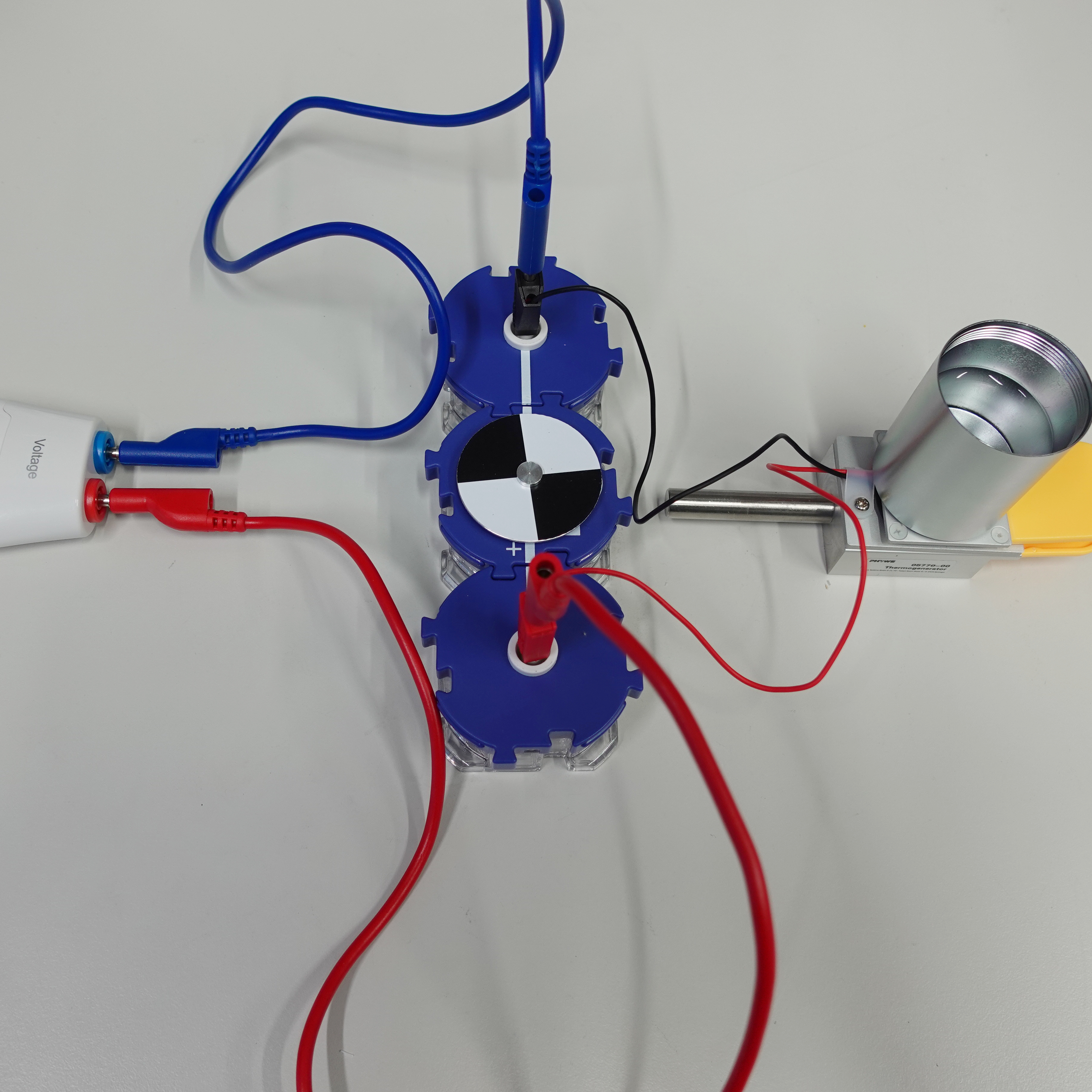 Motor mit Drehscheibe, der mit einem Spannungsmessger&auml;t und mit einem Peltierelement verbunden ist, auf dem ein Becher mit Wasser steht